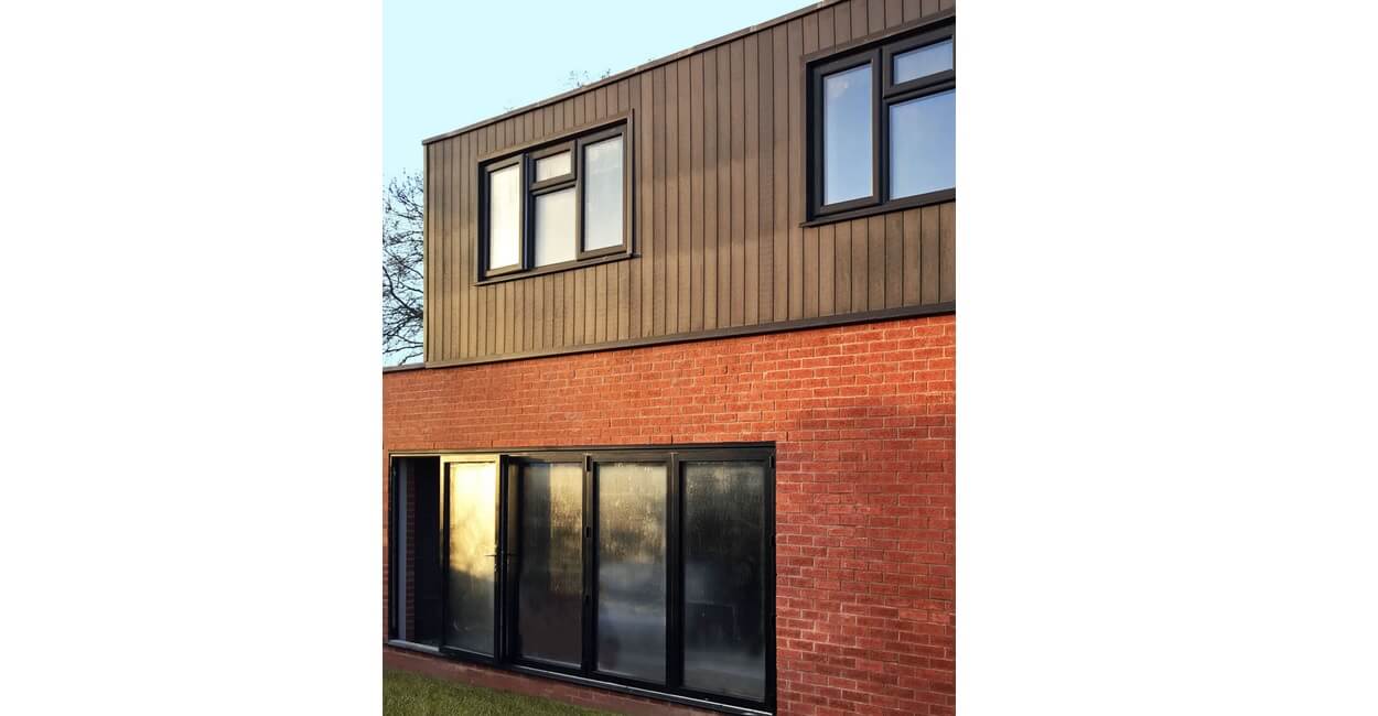 Composite Wall Cladding Boards in Charcoal contrast the existing red bricks on this home exterior