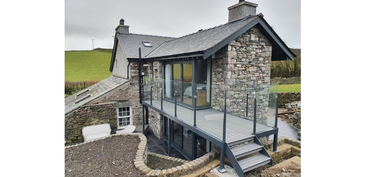 Stone Grey Raised Decking encircles this traditional stone wall cottage.