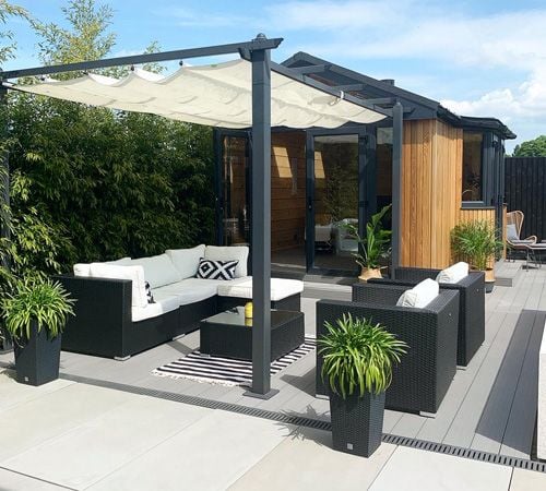 A Contemporary outdoor decking area with ample seating and soft furnishings and large paving slabs