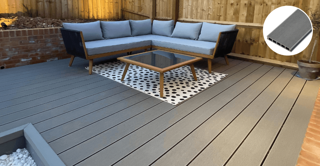 Stone grey decking with a spotty rug and garden sofa
