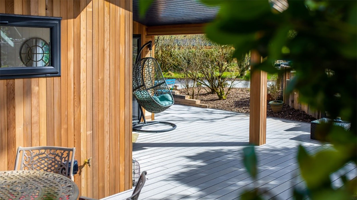 Grey Composite Decking with furniture on installed next to a timber holiday home in the countryside.