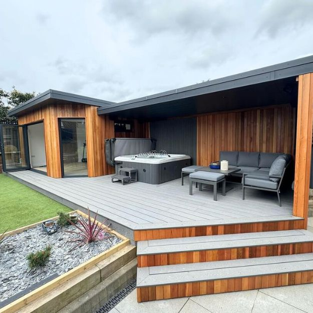 Grey Composite Decking with a lounge and hot tub area next to a small outhouse.