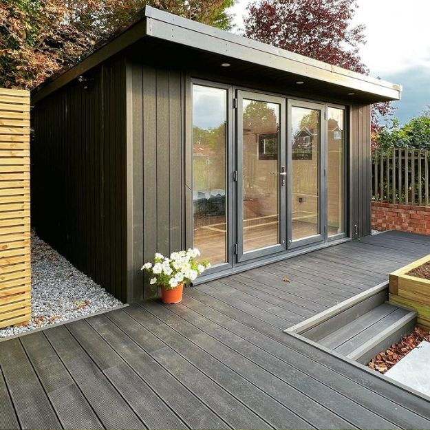 Garden room with Charcoal Composite Decking surrounding it, with a step leading down to the rest of the garden.
