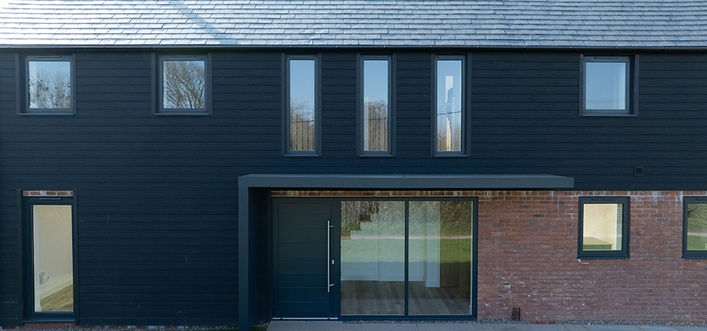 Front-facing view of this charcoal-clad house using Cladco Signature composite wall cladding in charcoal.