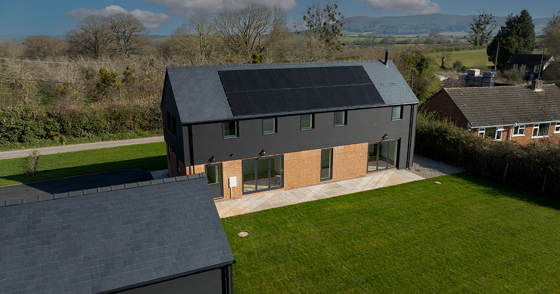 Aerial view of a modern Hereford home featuring Cladco Signature Charcoal Composite Wall Cladding, red brick lower exterior, and roof-mounted solar panels
