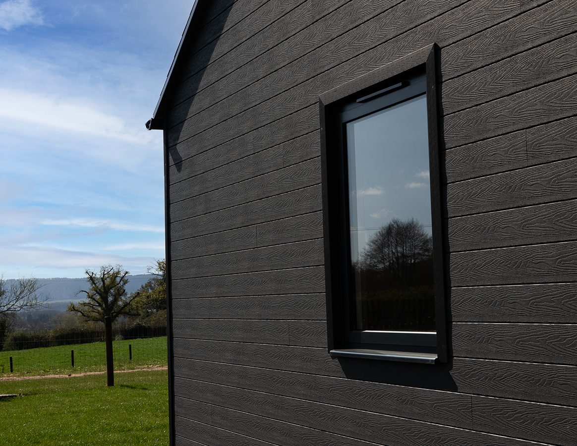Charcoal wall cladding installed surrounding a window on a contemporary house.