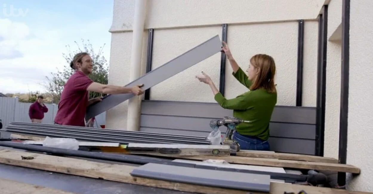 A man and a woman installing grey cladding boards